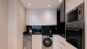 A compact kitchen with a dishwasher, washing machine, and double oven.