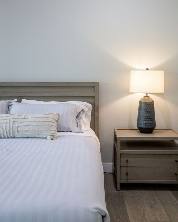 A neatly made bed with pillows and a bedside table with a lamp.