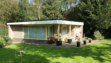 A modern building with a covered porch, a small garden, and a globe sculpture.