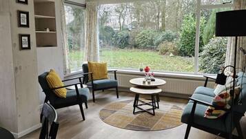 A living room with a large window, a round coffee table, and two armchairs.