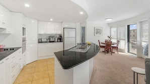 A modern kitchen with white cabinets, a black countertop, and a dining area with a table and chairs.