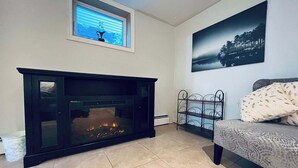 A living room with a fireplace, a sofa, a window with blinds, and a painting on the wall. - 1 bedroom apartment, centrally located and newly renovated (Moncton)