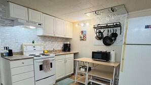 A compact kitchen with white cabinets, a stove, a microwave, and a small table. - 1 bedroom apartment, centrally located and newly renovated (Moncton)