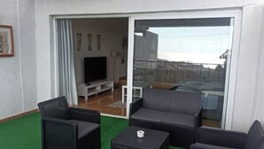 Un balcon doté de meubles en osier, d’un téléviseur à écran plat et offrant une vue sur la ville.