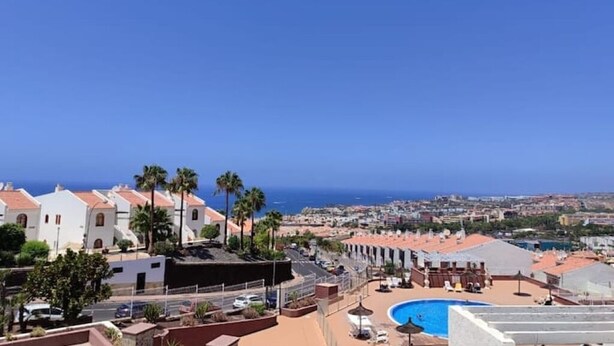 Un hôtel en bord de mer, doté d’une piscine, de palmiers et offrant une vue sur l’océan.