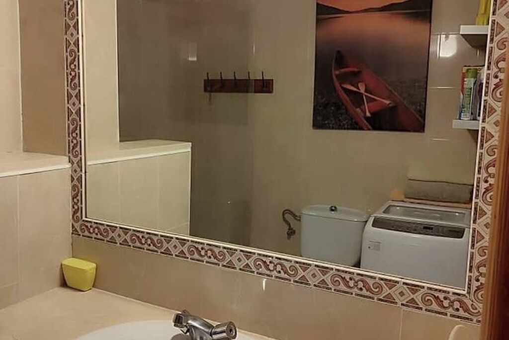 Et badeværelse med et stort spejl, toilet, håndvask og et håndklædestativ.