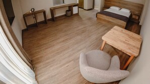 A hotel room with a bed, a desk, a chair, a small table, a bench, a trash bin, and a mirror. - Karasu Riva Otel (Karasu)