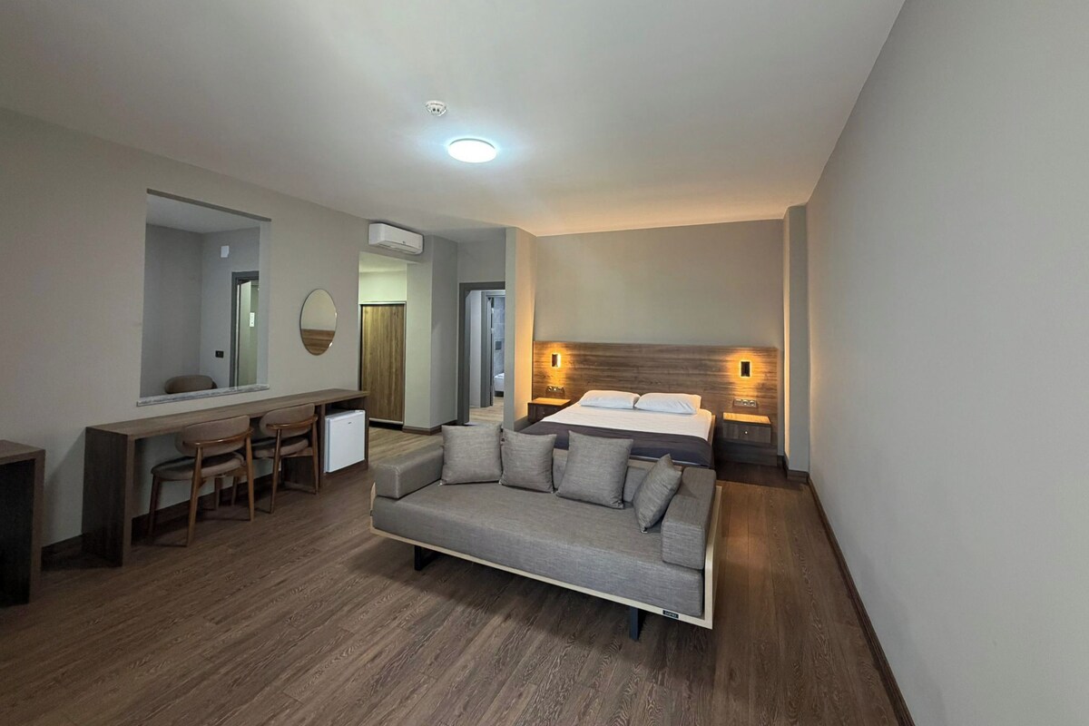 Une chambre d’hôtel moderne équipée d’un lit, d’un canapé, d’un bureau et d’un miroir.
