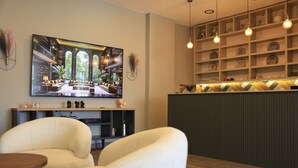 A hotel lobby with a large TV screen, comfortable seating, a reception desk, and a decorative wall with shelves. - Karasu Riva Otel (Karasu)