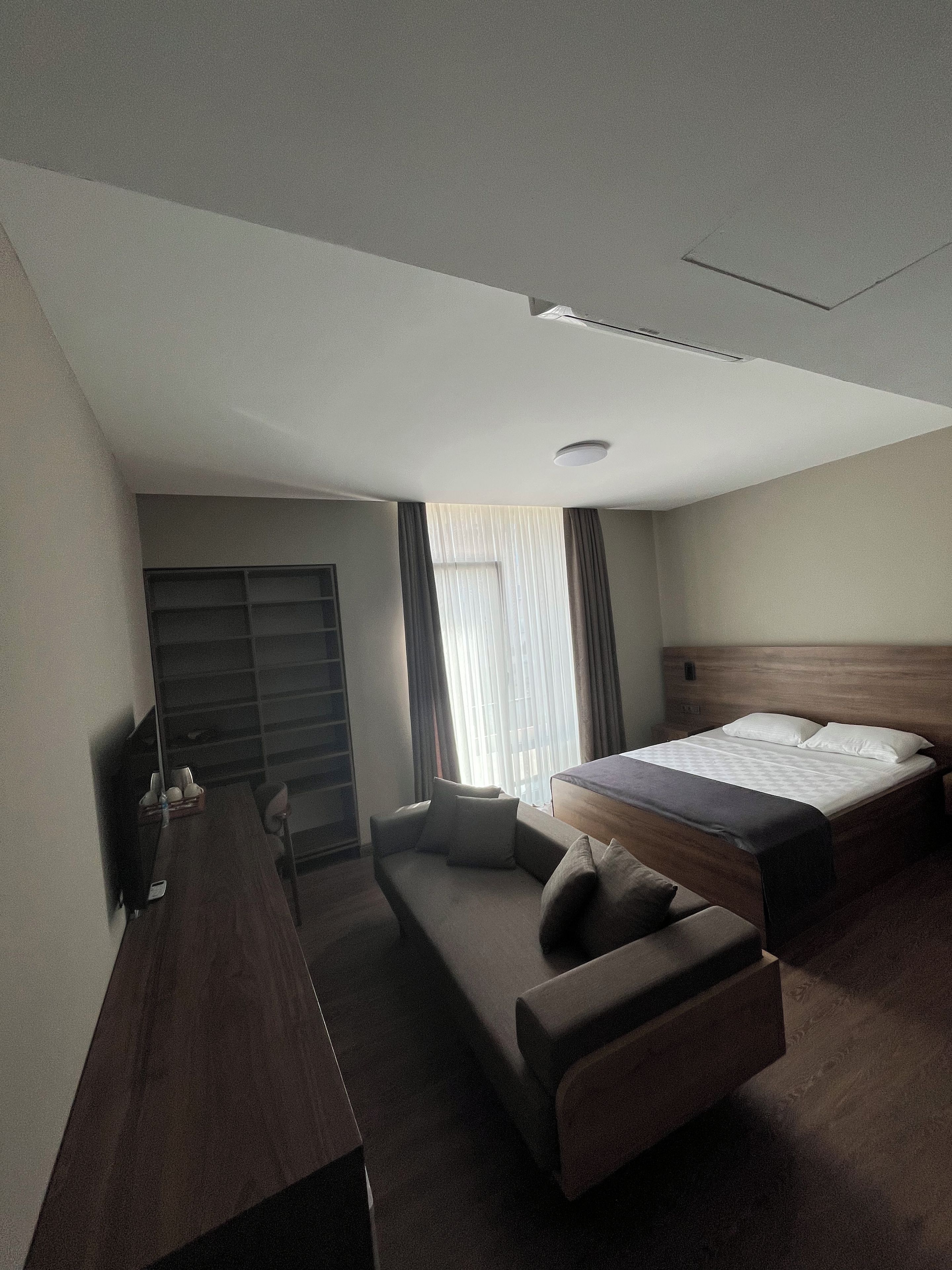 Ett hotellrum med en säng, en soffa, ett skrivbord och ett fönster med gardiner.