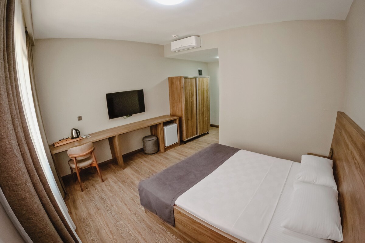 Une chambre d’hôtel comprenant un lit, un bureau avec une télévision, une armoire et une poubelle.