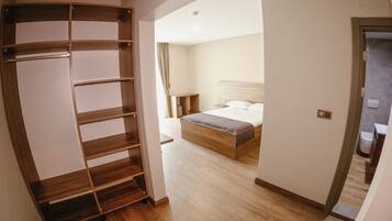 A bedroom with a wooden wardrobe, a bed with a mattress and pillows, and a nightstand.