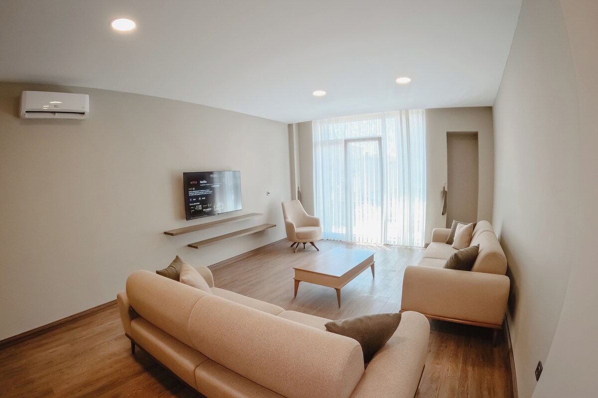Un salon moderne avec un canapé, une table basse et un téléviseur fixé au mur.