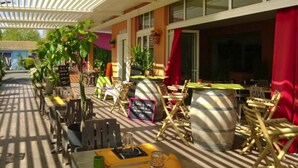 An outdoor dining area with tables and chairs, potted plants, and a large barrel. - Sea Stay for Six in Vias Plage (Vias)