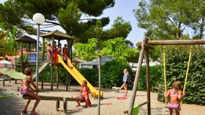 A playground with slides and swings, surrounded by trees and a covered play area. - Mobile Home in Bessan With Terrace (Bessan)