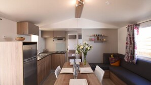 Une cuisine compacte avec des meubles en bois, une cuisinière encastrée et un coin repas avec une table dressée pour deux personnes.