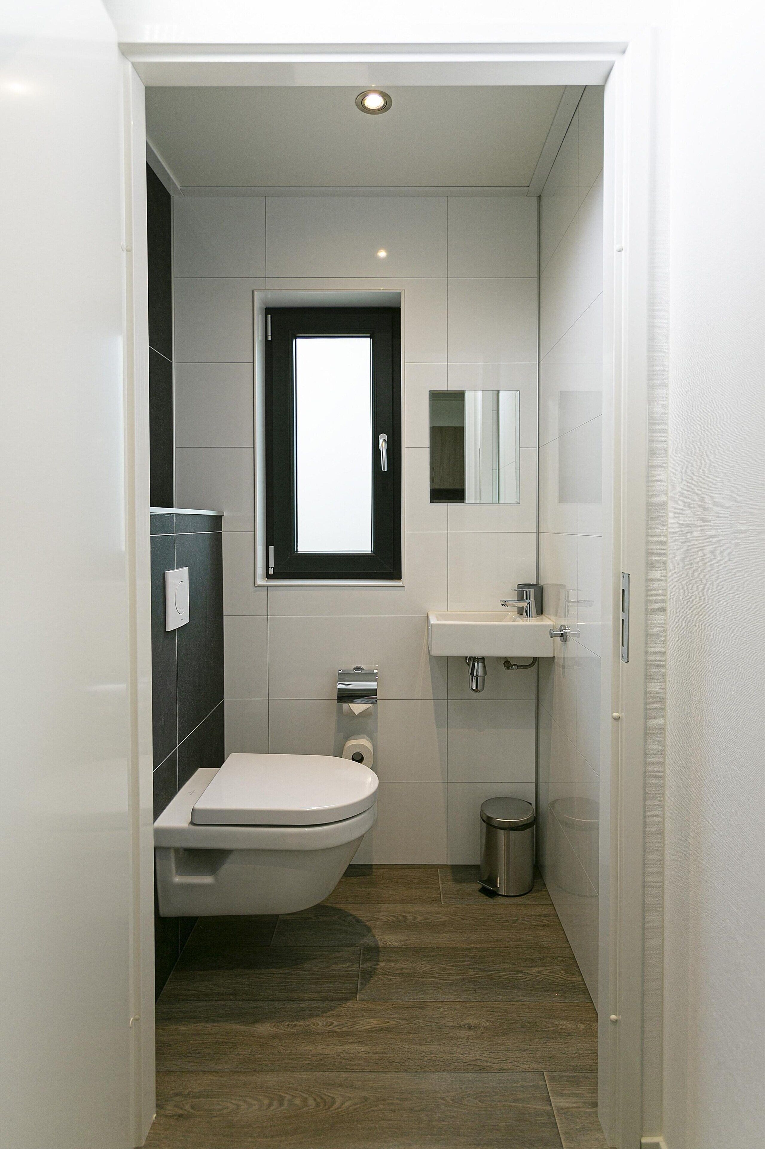 Une petite salle de bain comprenant des toilettes, un lavabo et un miroir.