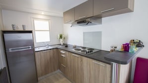 A compact kitchen with a refrigerator, sink, stove, and wooden cabinets. - Mobile Home in Serignan With Great Pool Area (Sérignan)