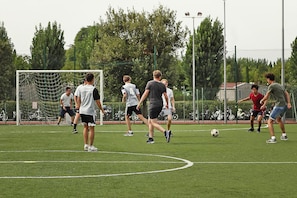 Un terrain de football avec des joueurs, des poteaux de but et un filet.