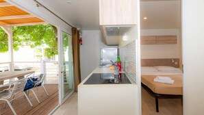 A compact room with a kitchenette, a bed, and a dining area with a table and chairs. - The Garda Village Caravan Park, Sirmione (Sirmione)