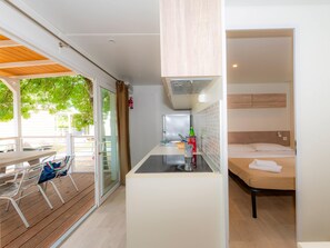 A compact room with a kitchenette, a bed, and a dining area with a table and chairs. - The Garda Village Caravan Park, Sirmione (Sirmione)