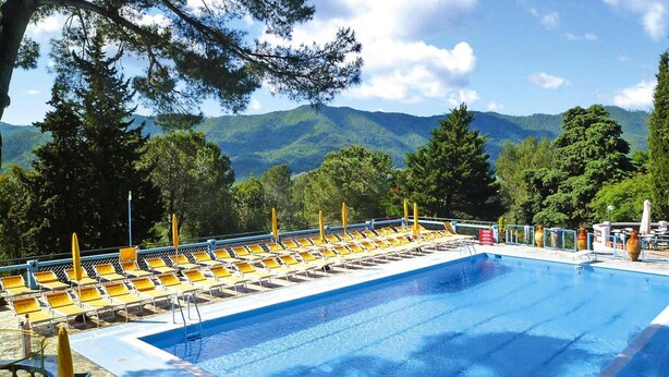 Une piscine avec des chaises longues jaunes et une vue sur les montagnes.