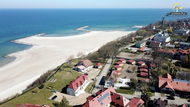 An aerial view of a coastal residential area with houses, a beach, and a pier. - 2 Bedroom Holiday Home in Jaroslawiec (Postomino)