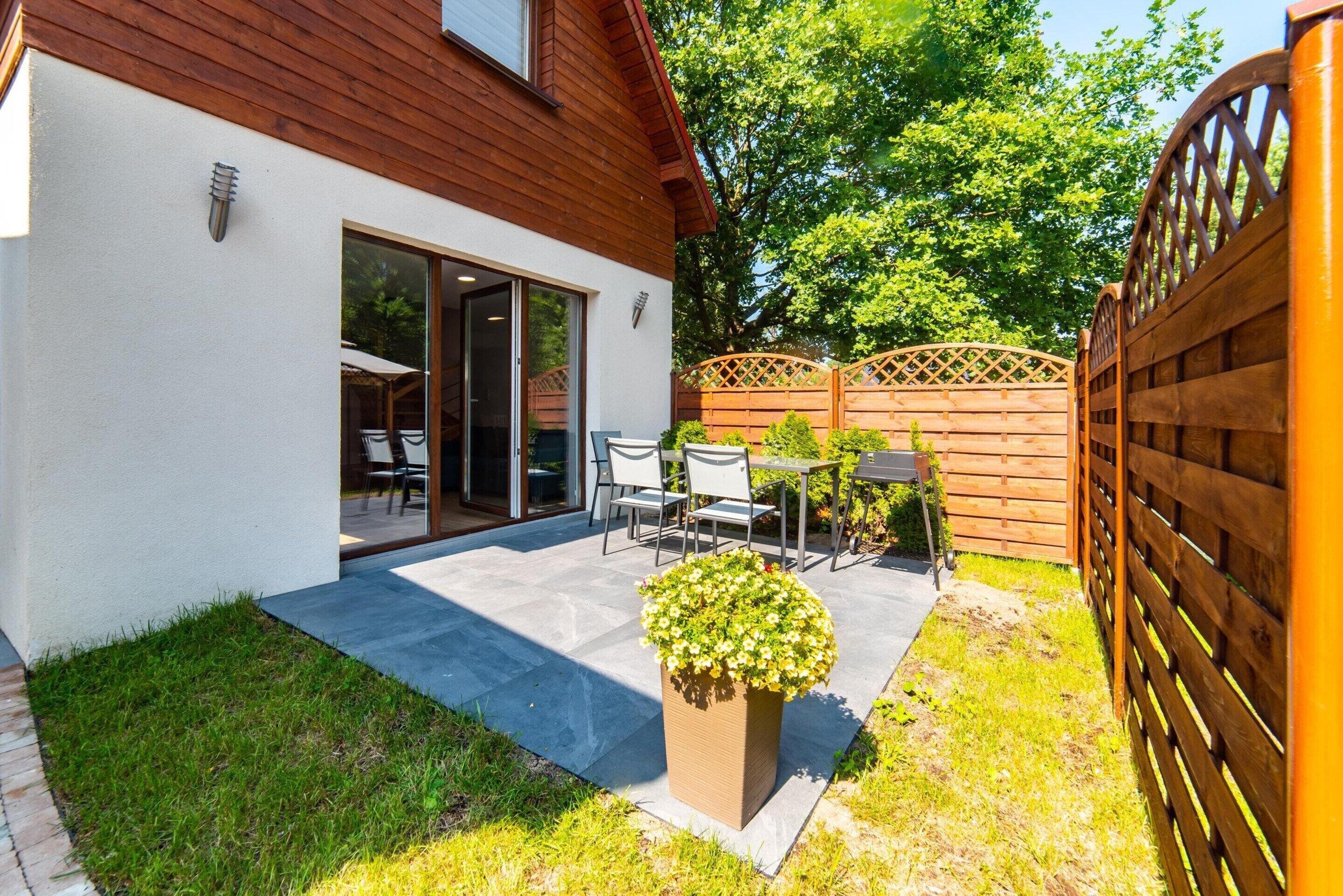 A modern house with a patio, a wooden fence, and a potted plant.