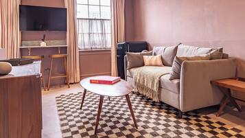 Una sala de estar moderna con un sofá, una mesa de centro y un televisor montado en la pared.