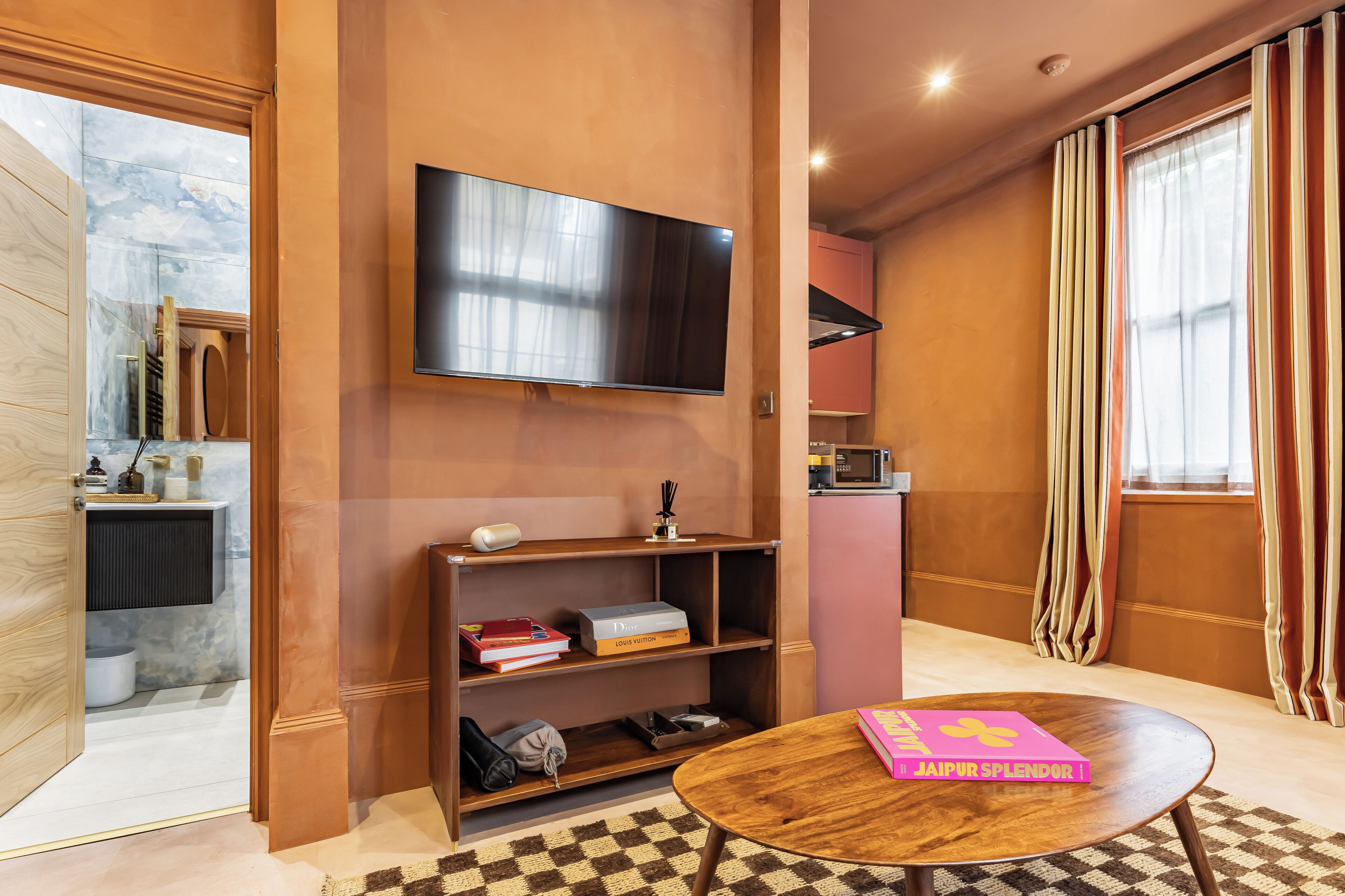 A modern living room with a flat-screen TV, a wooden coffee table, and a bookshelf.