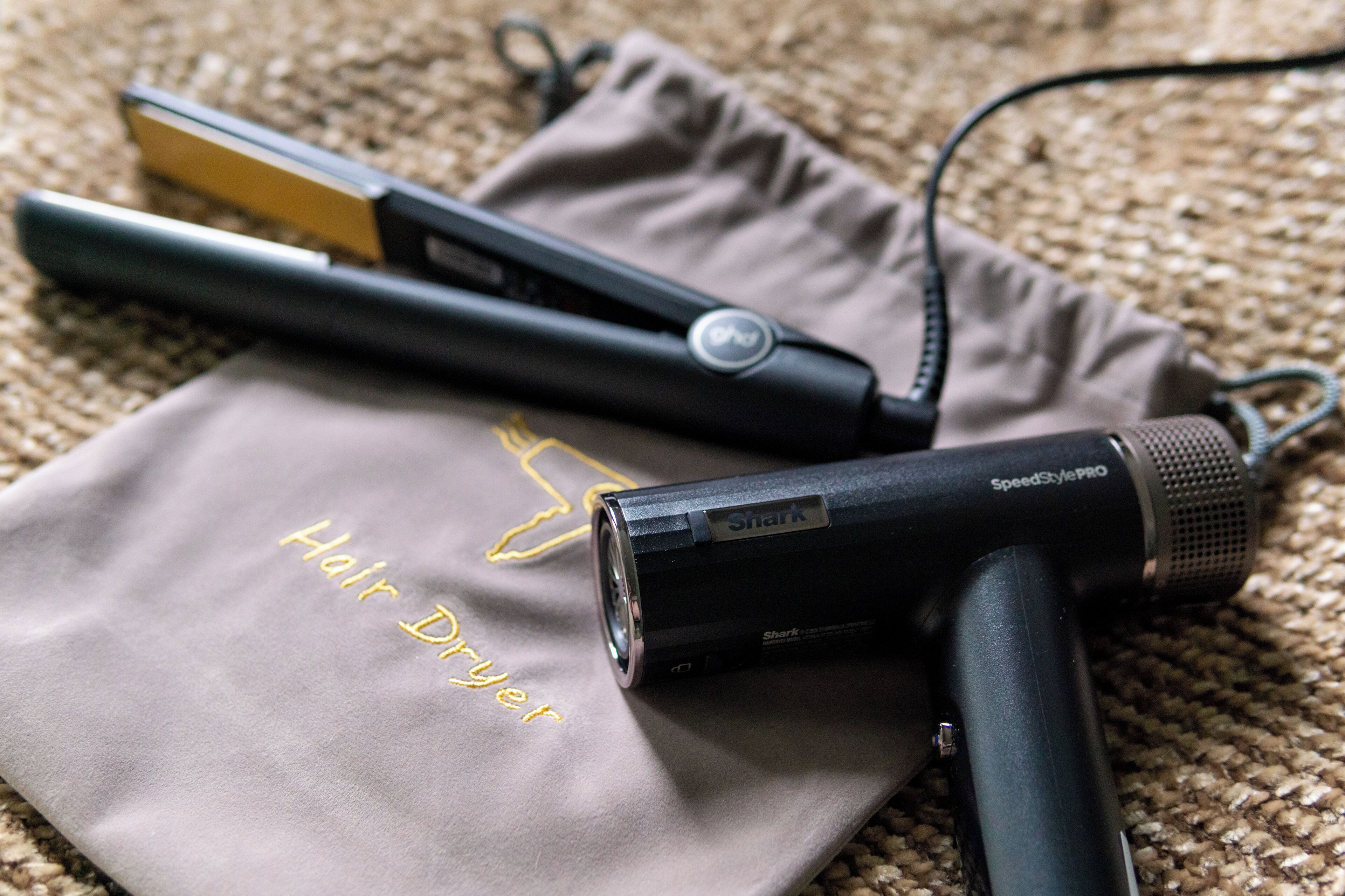 A hair straightener and a hair dryer on a textured surface.