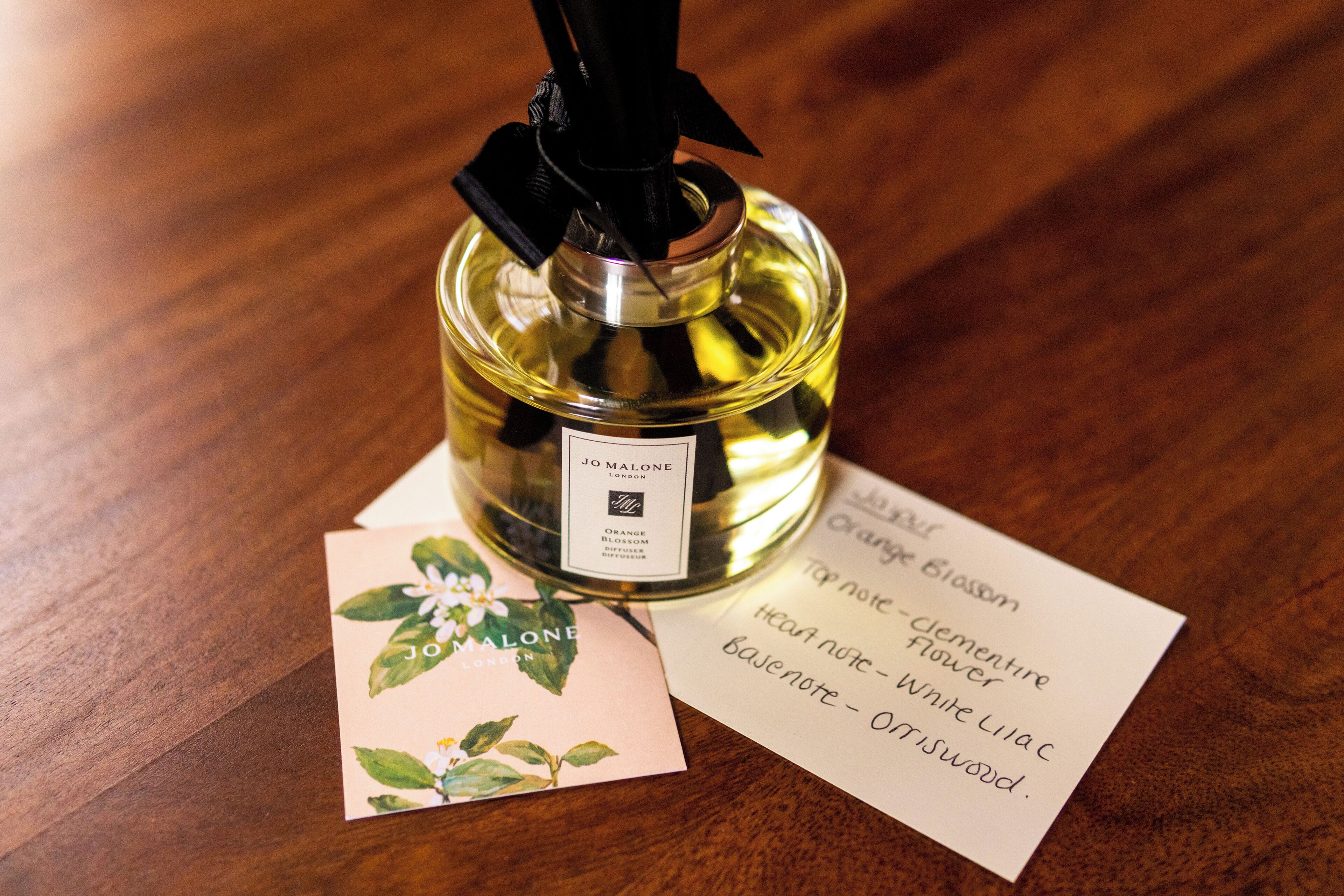 A bottle of perfume with a label and a card with floral design.