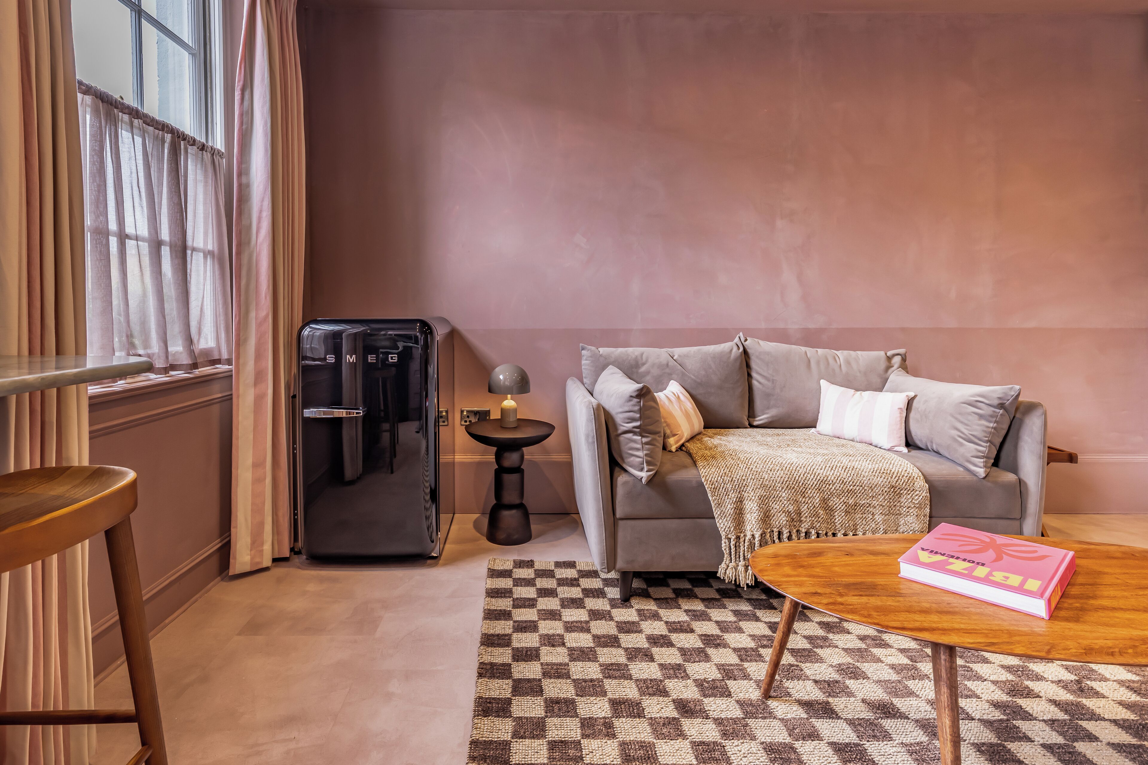 A cozy living room with a grey sofa, a wooden coffee table, and a checkered rug.