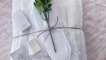 A neatly arranged set of towels, a rose, and a small card on a textured bedspread.