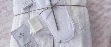 A neatly arranged set of towels, a rose, and a small card on a textured bedspread.