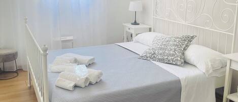Une chambre bien rangée, avec un lit, des tables de chevet, une lampe et une fenêtre avec des rideaux.