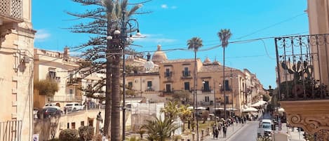 Una calle con edificios, coches aparcados y peatones.
