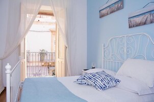 Un dormitorio con cama, cortinas blancas y un balcón.