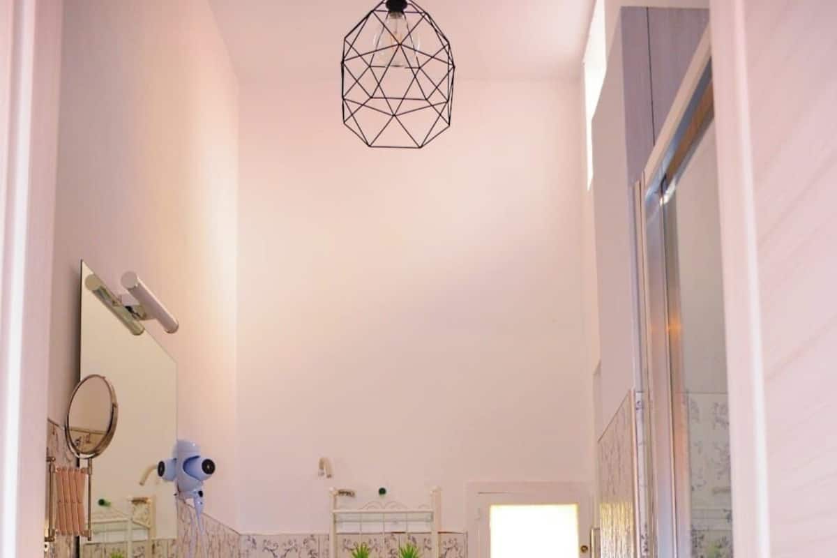 Un baño con lavamanos blanco, espejo y zona de ducha.