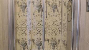 A walk-in shower with a glass door, a toilet, and patterned tiles.