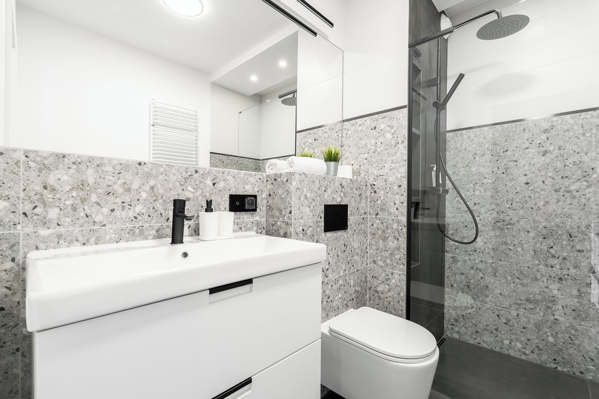 Een moderne badkamer met een wit wastafel, toilet en een douchecabine met glazen wanden.