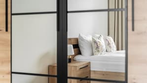 A bedroom with a wooden headboard, a bedside table with a lamp, and floral-patterned pillows. - MARGI Verde Apartament (Szczecin)