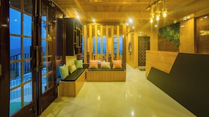Interior moderno com painéis de madeira, área de estar com almofadas e janelas amplas.