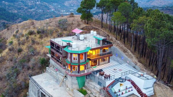 A multi-story building with a rooftop terrace, a balcony, and a staircase leading to the upper floors.