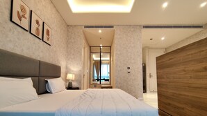 Ett modernt hotellrum med en stor säng, en garderob i trä och en spegel som reflekterar rummet.