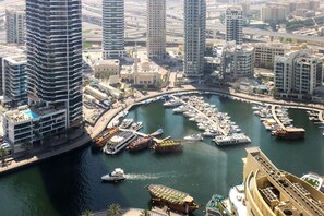 A marina with numerous boats docked, surrounded by high-rise buildings and a prominent mosque.