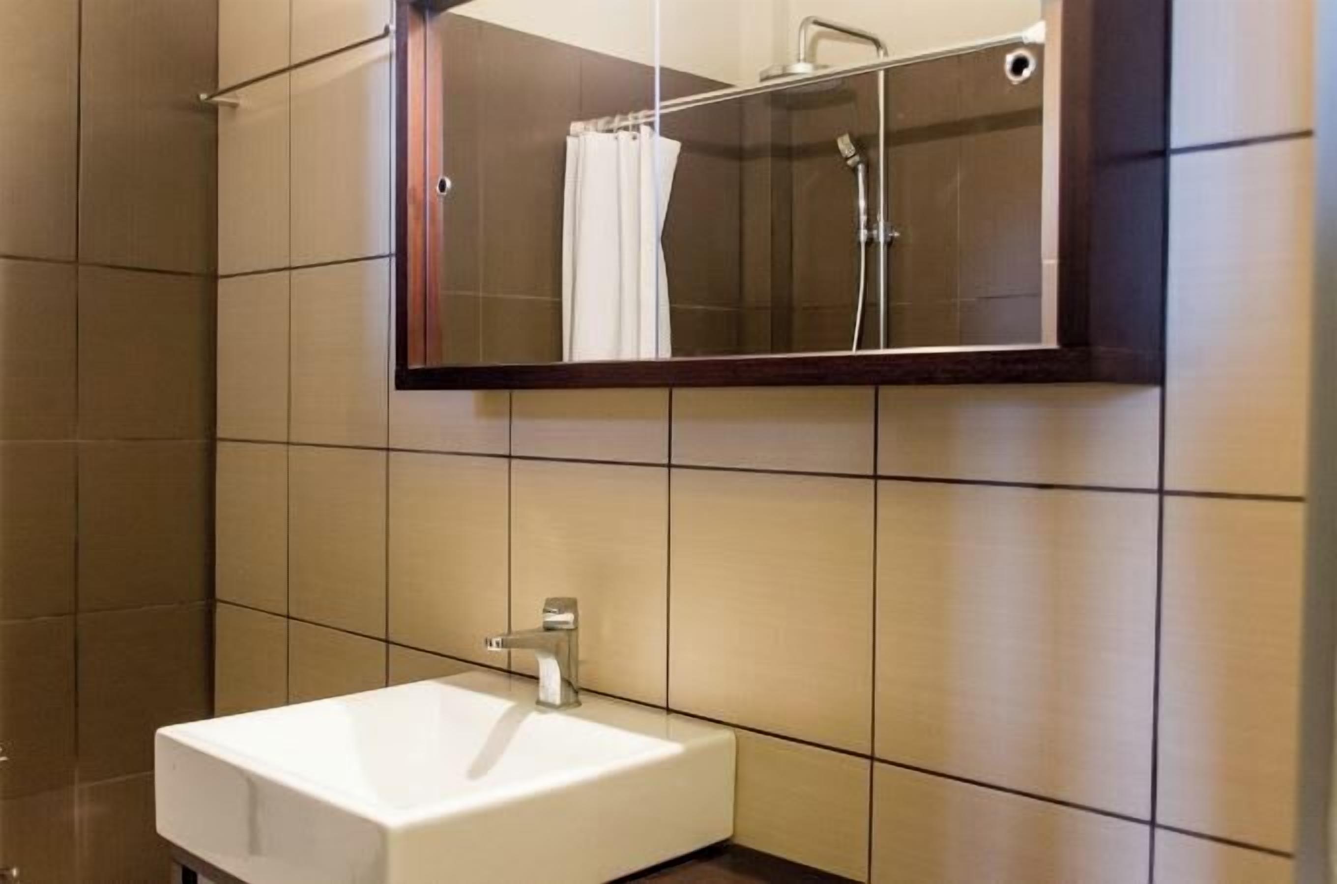 Ein Badezimmer mit einem weißen Waschbecken, einem Spiegel und einer Dusche.