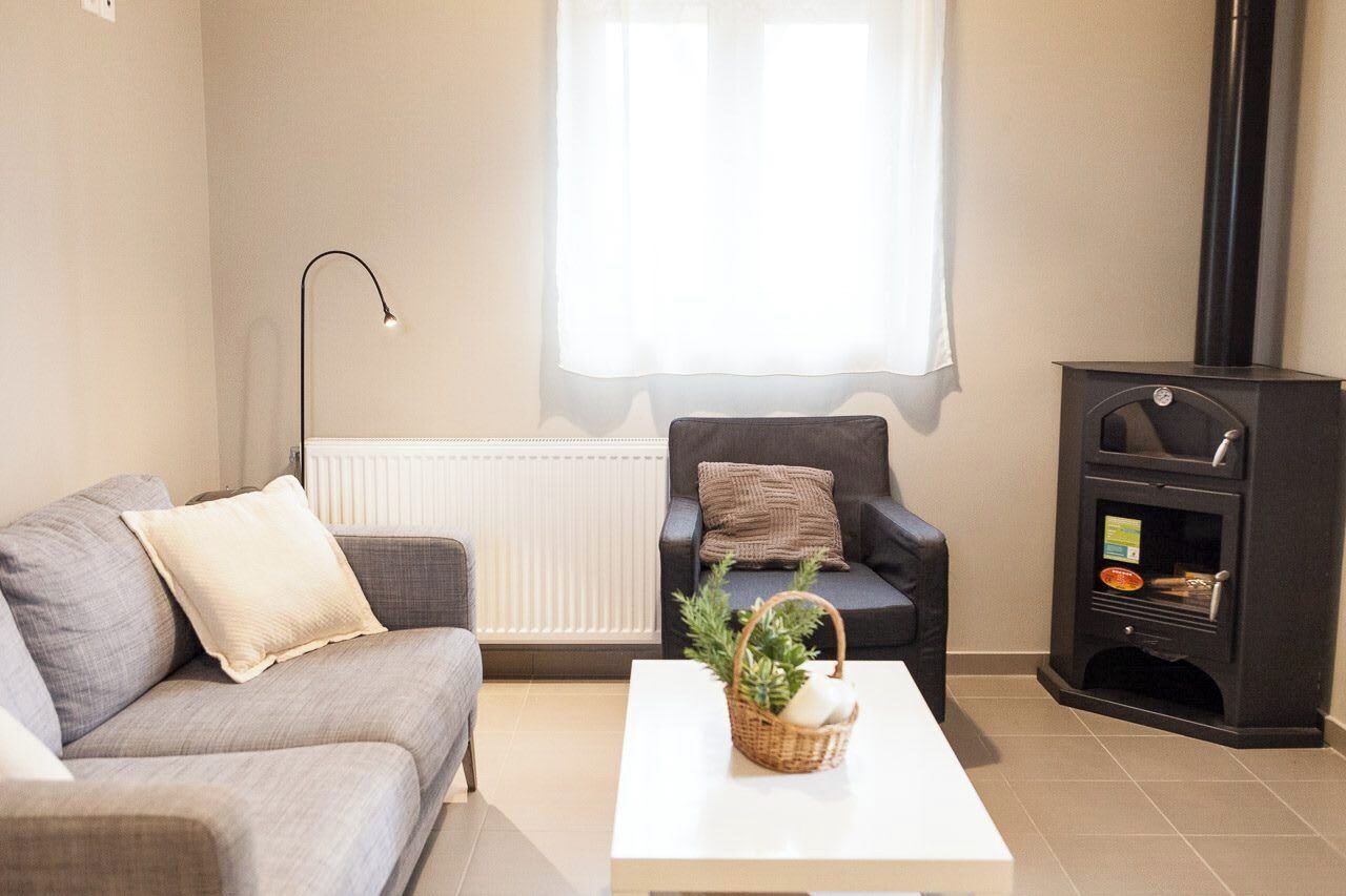 A living room with a sofa, armchair, and a black wood-burning stove.