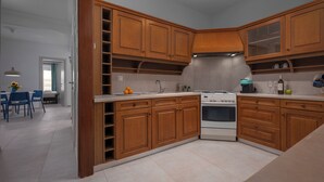 A modern kitchen with wooden cabinets, a built-in oven, and a dining area with blue chairs. - Located above Aristotelous Sq, near cafes, sights & tasty local bites (Thessaloniki)