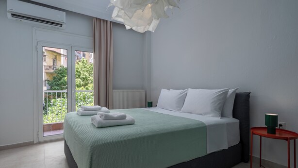 A bedroom with a bed, a nightstand, a window with curtains, and a view of greenery outside. - Located above Aristotelous Sq, near cafes, sights & tasty local bites (Thessaloniki)